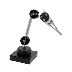 May include: A black and silver third hand soldering tool with a swivel base and adjustable arms. The tool is designed to hold small objects in place while soldering.