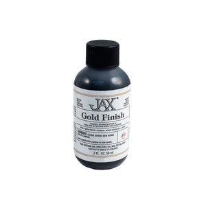 Könnte beinhalten: Eine kleine Flasche JAX Gold Finish Lösung. Die Flasche ist schwarz mit einem weißen Etikett, auf dem "JAX Gold Finish" steht und Anweisungen zur Verwendung und Warnhinweise enthalten sind. Die Flasche enthält 59 ml.