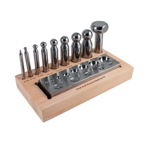 May include: A set of 12 oval and round metal dapping punches and dies in a wooden holder. The set includes a variety of sizes, ranging from 3 mm to 25 mm. The holder has a label that reads "Oval And Round dapping Kit".