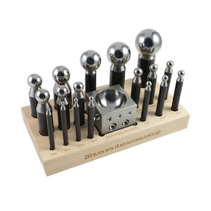 May include: A set of 19 metal dapping punches and a wooden dapping block. The punches are arranged in a wooden holder with a label that reads "2x2 Block with 18 pcs Matching Punch Set".