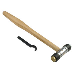 Puede incluir: Un martillo con mango de madera, cabeza de latón y una llave de metal negra. El martillo está diseñado para colocar metal.