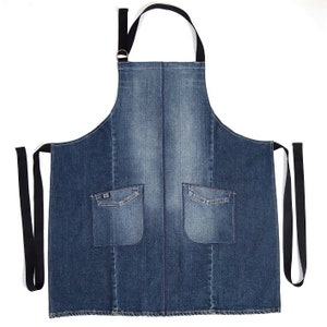 Op de afbeelding: Een blauwe denimschort met twee grote zakken en verstelbare zwarte banden. De schort is gemaakt van duurzaam, zwaar denim.