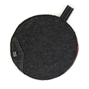May include: A round black denim pot holder with a small pocket that says "design intoa" on it. The pot holder has a loop handle.