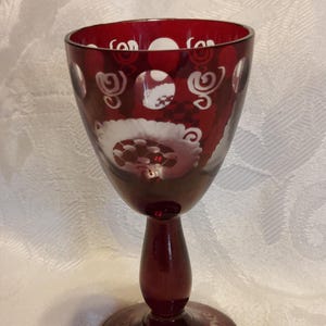 May include: A white ceramic mug with a black handle and the text "But First, Coffee" in a bold, black font. The mug is set against a blurred background, suggesting a cozy setting.