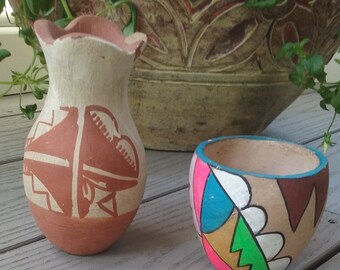 Peut inclure: Deux petits vases en poterie peints à la main. Le plus grand vase est brun avec un motif géométrique. Le plus petit vase est brun avec un motif géométrique coloré.
