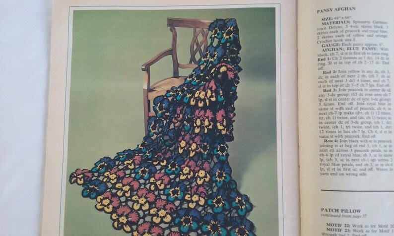 May include: A crochet pattern for a pansy afghan, featuring a close-up of the finished product draped over a wooden chair. The afghan is made with a variety of colors, including blue, yellow, red, and green. The pattern includes instructions for creating the pansy motif, as well as the overall afghan.