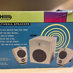 May include: A box of KLH Audio Systems multimedia speakers. The box is blue and green with the text "MULTIMEDIA SPEAKERS". The speakers are grey and include a subwoofer and two satellite speakers. Features include 32 watts total amplifier power and USB ready.