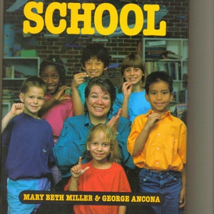 May include: A book cover with the title "HANDTALK SCHOOL" in yellow letters on a brick background. The cover features a group of children and an adult woman, all signing with their hands. The book's authors are listed as "MARY BETH MILLER & GEORGE ANCONA".