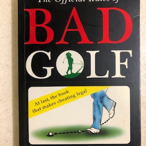 May include: A book titled "The Official Rules of BAD GOLF" with red and white lettering on a black background. The cover features a golf-themed illustration and the text "At last, the book that makes cheating legal."