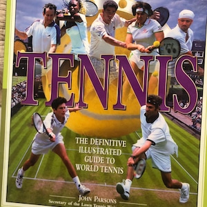 May include: A book cover titled "THE ULTIMATE ENCYCLOPEDIA OF TENNIS". The cover features images of tennis players in action, with the word "TENNIS" in large, purple letters. The text "THE DEFINITIVE ILLUSTRATED GUIDE TO WORLD TENNIS" is also visible.