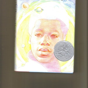May include: The Planet of Junior Brown by Virginia Hamilton, a children's book cover with a watercolor illustration of a young Black boy with a light blue background and a Newbery Award sticker.