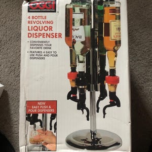 May include: A chrome liquor dispenser with four bottles and four push and pour dispensers. The box features the text "4 Bottle Revolving Liquor Dispenser" and "New Easy Push & Pour Dispensers".