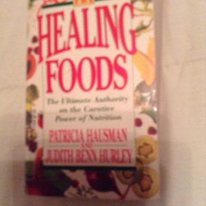 May include: A book titled "Healing Foods: The Ultimate Authority on the Curative Power of Nutrition" by Patricia Hausman and Judith Benn Hurley. The cover features a colorful design with fruits and vegetables.