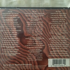May include: A two-disc CD set with a woodgrain background. The front of the CD case features the title "Sony Music Special Products" and the text "This compilation 2001 Sony Music Entertainment Inc.". The back of the CD case lists the songs on each disc. The songs are a mix of country, folk, and pop music.