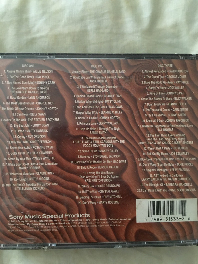 May include: A two-disc CD set with a woodgrain background. The front of the CD case features the title "Sony Music Special Products" and the text "This compilation 2001 Sony Music Entertainment Inc.". The back of the CD case lists the songs on each disc. The songs are a mix of country, folk, and pop music.