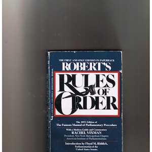 May include: A blue book cover with the title "Robert's Rules of Order" in white lettering. The book is the 1893 edition of the famous manual of parliamentary procedure. The book cover also includes the names Rachel Vixman and Floyd M. Riddick.