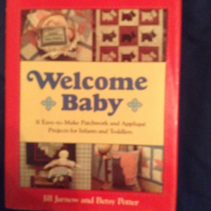 Puede incluir: Un libro rojo titulado "Welcome Baby" con un subtítulo amarillo "Easy-to-Make Patchwork and Applique Projects for Infants and Toddlers". La portada presenta una colcha de retazos con un diseño de perro y una muñeca en un ambiente de habitación.