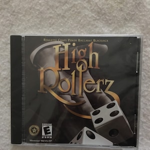 May include: A computer game CD case with a black background and gold lettering. The title of the game is "High Rollerz" and the game features roulette, craps, poker, baccarat, and blackjack. The ESRB rating is "Everyone".