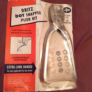 May include: A silver Dritz Dot Snapper Plier Kit with a long handle and a pack of 4 dot snappers. The packaging says "Just squeeze to attach snappers!" and "Laundryproof Rustproof".