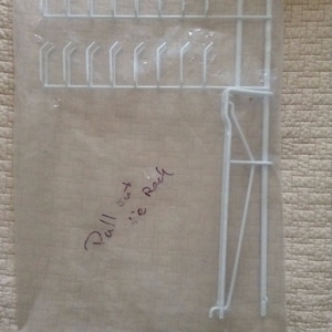 May include: White metal ball out size rack, packaged in clear plastic. The rack is designed to hold balls, with multiple hooks for storage.
