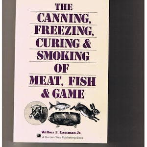 May include: Book cover with a white background and purple text that reads "The Canning, Freezing, Curing & Smoking of Meat, Fish & Game". The cover also features illustrations of a cow, fish, pig, and rabbit.