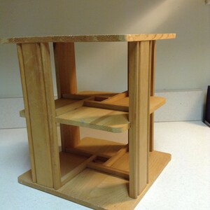 Könnte beinhalten: Ein Holzregal mit drei Ablagen. Die Ablagen sind aus dünnem Holz und werden von vier dickeren Holzpfosten getragen. Das Regal ist aus Naturholz gefertigt und hat einen rustikalen Look.