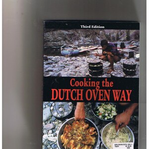 May include: A book cover with a photo of a person cooking over a campfire using a Dutch oven. The book title is "Cooking the Dutch Oven Way" and the author is Woody Woodruff. The book is in its third edition and was revised by Ellen Woodruff Anderson and Jane Woodruff.