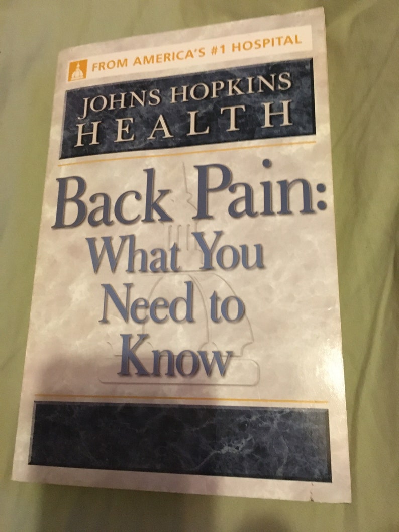 Puede incluir: Una portada de libro con fondo blanco y texto azul y negro. El t&iacute;tulo es "Back Pain: What You Need to Know" y el subt&iacute;tulo es "Johns Hopkins Health".