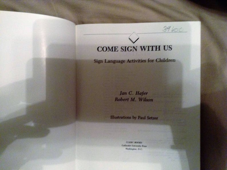 May include: A book titled "Come Sign With Us: Sign Language Activities for Children" by Jan C. Hajer and Robert M. Wilson. The book cover features a diamond shape and the title in black text.