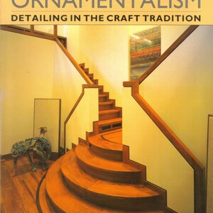 May include: Book cover titled "ARCHITECTURAL ORNAMENTALISM" with the subtitle "DETAILING IN THE CRAFT TRADITION." The image shows a wooden staircase with curved steps and a sculpture. The author is Jim Kemp, with photographs by Robert Perron.