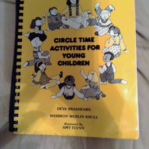 May include: A yellow book with a black spiral binding titled "Circle Time Activities for Young Children". The cover features a colorful illustration of children sitting in a circle.