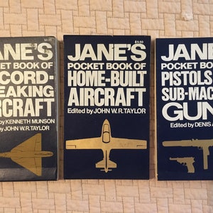 May include: Three vintage paperback books titled "Jane's Pocket Book of Record-Breaking Aircraft", "Jane's Pocket Book of Home-Built Aircraft", and "Jane's Pocket Book of Pistols and Sub-Machine Guns". Each book features a gold illustration of an aircraft or gun on a dark blue background.