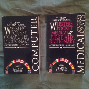 May include: Two black hardcover books with the title "Webster's Pocket Computer Dictionary" and "Webster's Pocket Medical & First Aid Dictionary" on the front covers. Both books have a new revised edition label and a rainbow of flags on the bottom of the cover.