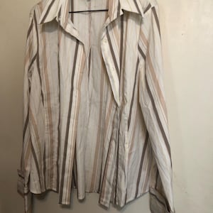 May include: A button-down shirt with vertical stripes in shades of beige, brown, and white. The shirt has long sleeves, a collared neckline, and the brand name "INSIGHT" is visible on the label.
