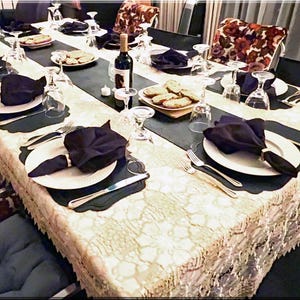 A table formally set with an ivory tablecloth and black dinner napkins.