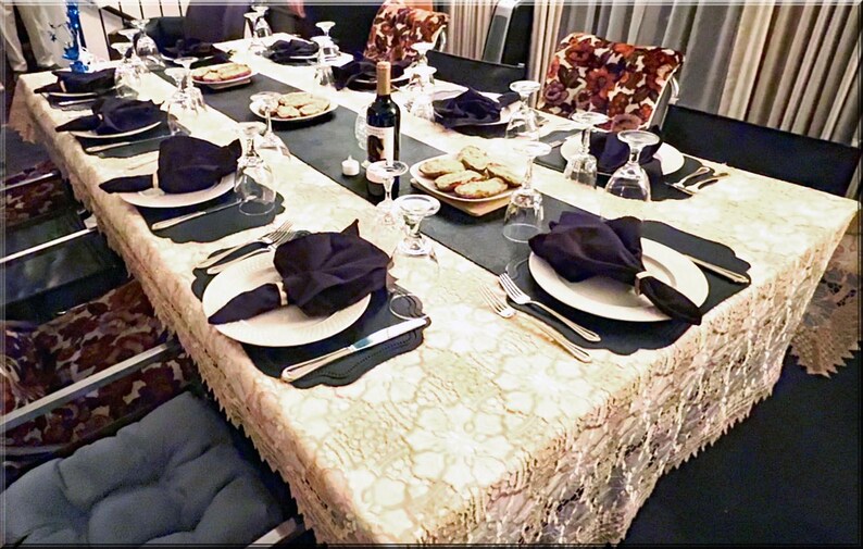 A table formally set with an ivory tablecloth and black dinner napkins.