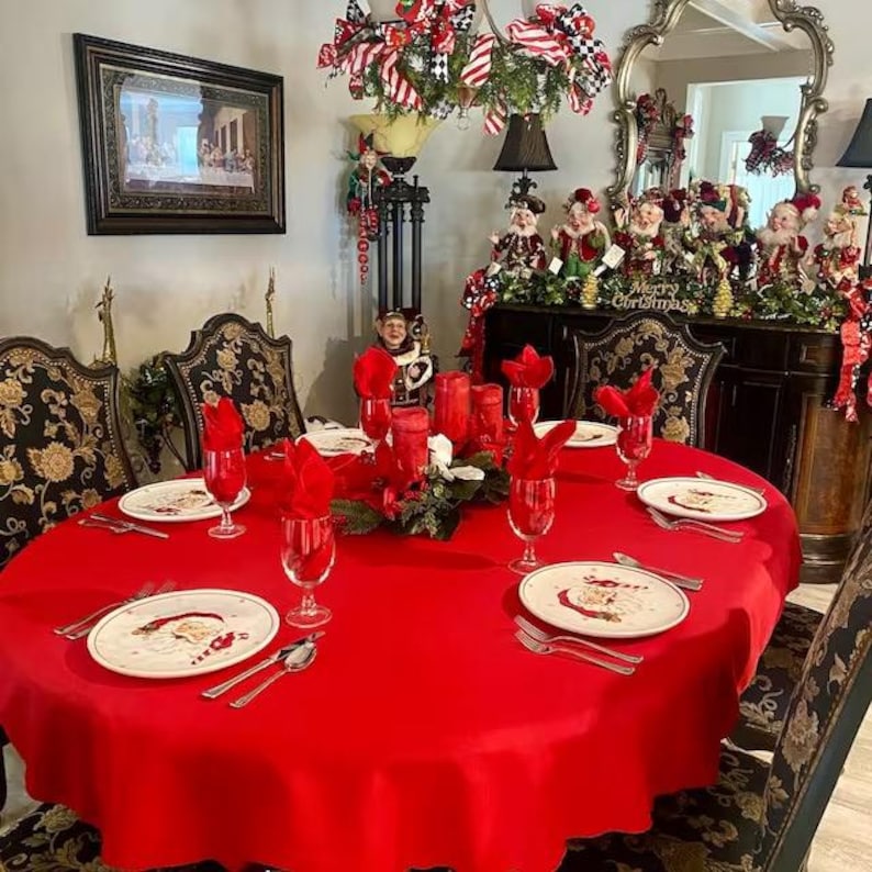 Holiday red oval tablecloth in a dining room during the holidays. The room is full of Christmas decorations as well as the red tablecloth. Looks very stunning.