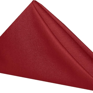 A folded red napkin. The napkin is a cotton napkin manufactured by Premier Table Linens.