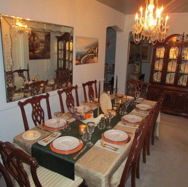 A green velvet table runner drapes over a tablecloth set for a dinner party.