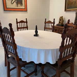 White velvet tablecloth. This oval tablecloth is in a beautiful home dining room with gorgeous paintings hanging.