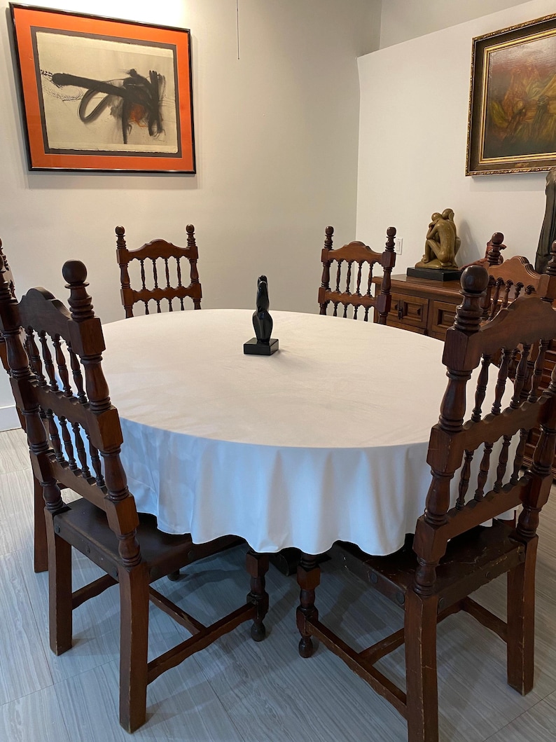 White velvet tablecloth. This oval tablecloth is in a beautiful home dining room with gorgeous paintings hanging.