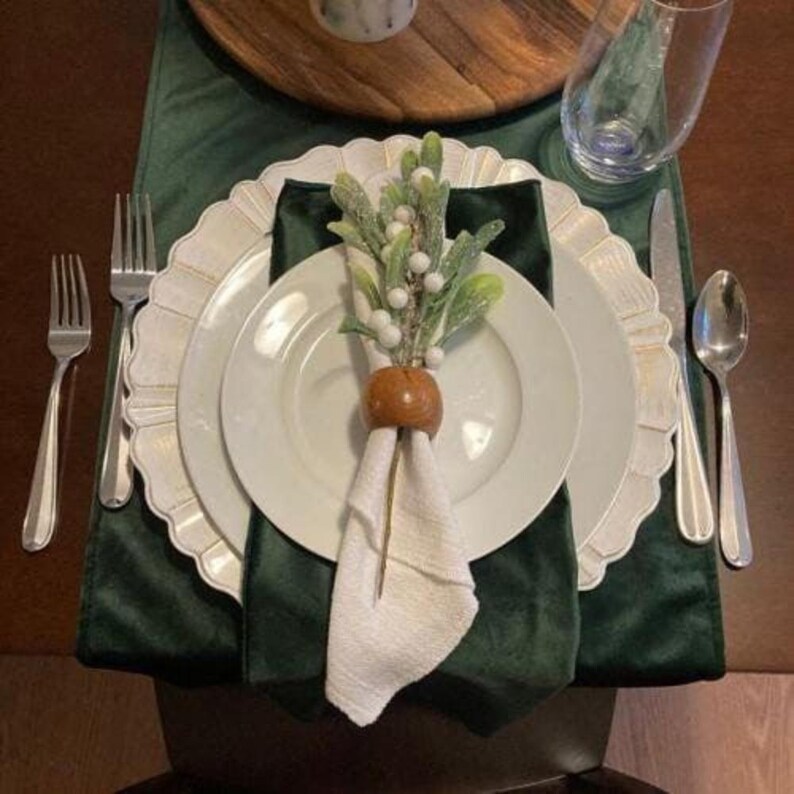 Green velvet table runner and white velvet napkin close up.