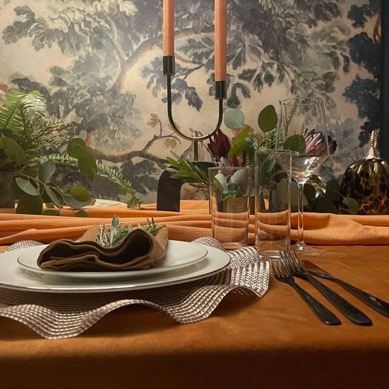 Beautiful burnt orange velvet tablecloth  with placemats and velvet napkins on top of the plate.