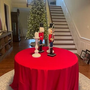 Red Christmas tablecloth in a home during the holidays with a Christmas tree in the hallway. It is a plush velvet tablecloth that looks stunning.