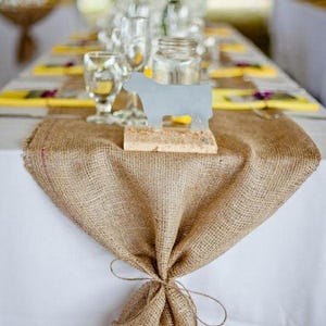a wedding reception with a long burlap table runner. The end of the burlap runner is tied off with jute rope.