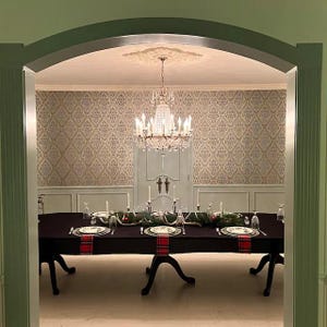 Black tablecloth and dinner napkins on a very large oblong table in a dining room with a beautiful chandelier.