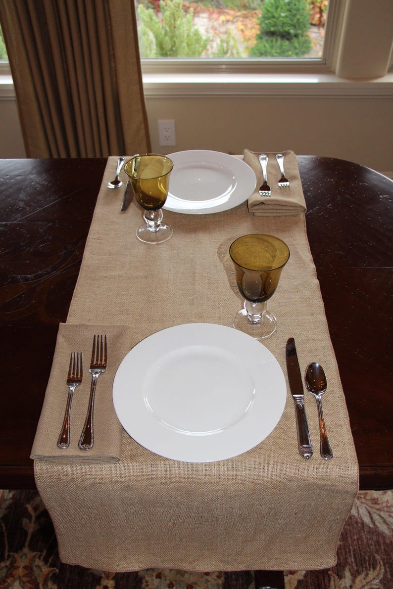 A table with a burlap table runner set for a meal for two.