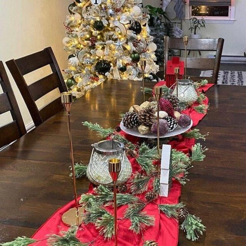A red velvet table runner drapes over a wooden table set for a dinner party.