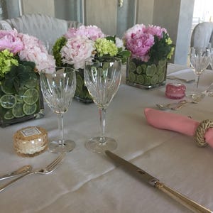 Linen tablecloth and twill cotton dusty rose napkins on a long rectangular table set for a formal meal.