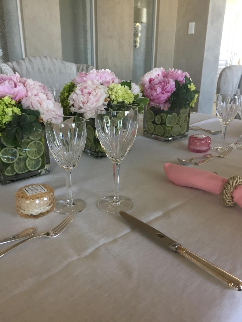 Linen tablecloth and twill cotton dusty rose napkins on a long rectangular table set for a formal meal.
